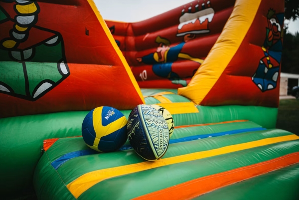 H�pfburg f�r Kinder.Blau-gelber Volleyball und Rugbyball auf bunter H�pfburg